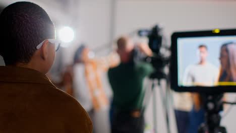 Actors-Shooting-Movie-Or-Video-In-Studio-With-Film-Crew-And-Female-Director-Watching-Monitor-In-Foreground